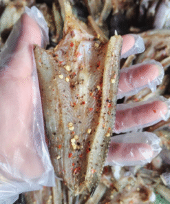 Khô cá lóc miếng có tiêu và ớt trên tay đeo bao tay