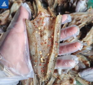 Khô cá lóc miếng có tiêu và ớt trên tay đeo bao tay